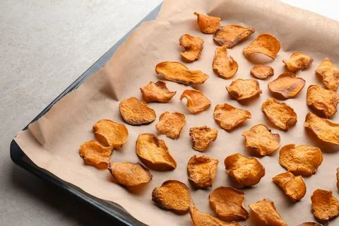 Baking sheet with sweet potato chips on grey background Stock-Fotos