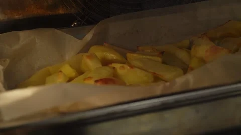 Baking sliced potatoes in a baking dish in the oven on baking paper, Homemade Stock Footage 272818959