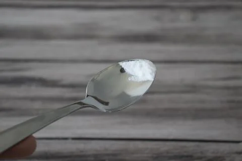 Baking soda on the tip of a small spoon on a wooden background Stock Photos