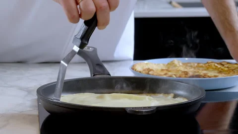 Baking thin pancakes crepes The pan with pancakes is moved on the electric stove Stock Footage 302646566