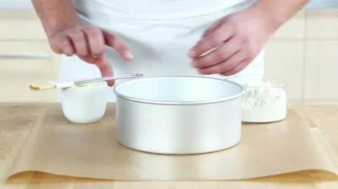 A baking tin being spread with butter and dusted with flour Stock Footage 24671623