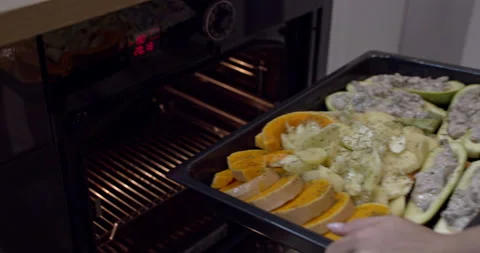 Baking tray full of vegetables and meat is put in the oven to cook. Slow motion. Stock Footage 144815722
