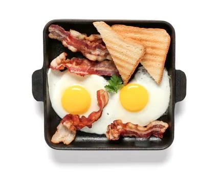 Baking tray with tasty fried eggs, bacon and toasted bread isolated on white  Stock Photos