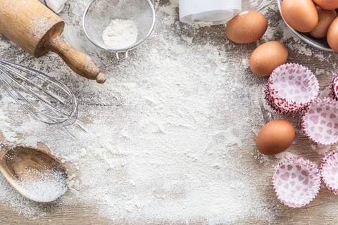 Baking utensils with eggs flour and cupcake cases on kitchen table - Top of.. Stock Photos