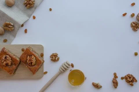 Baklava on a board on a light background next to nuts, honey and raisins Stock Photos