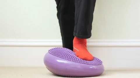 Balance board ankle exercise purple inflatable wobble feet close up Stock Footage 100472310