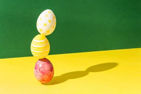 Balance easter eggs on a green and yellow background hard light black shadows Stock Photos