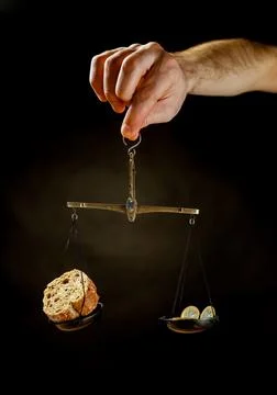 Balance scale with piece of bread on one pan and Euro coins on the other pa Stock Photos