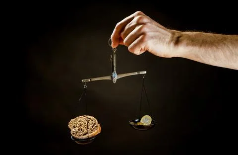 Balance scale with piece of bread on one pan and Euro coins on the other pan Stock Photos