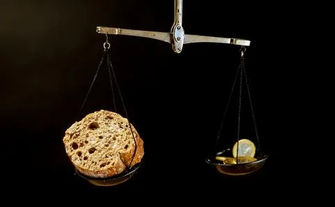 Balance scale with piece of bread on one pan and Euro coins on the other pan Stock Photos