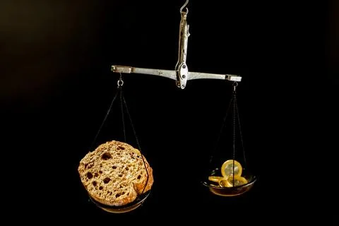 Balance scale with piece of bread on one pan and Euro coins on the other pan Stock Photos
