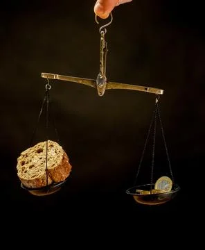 Balance scale with piece of bread on one pan and Euro coins on the other pan Stock Photos