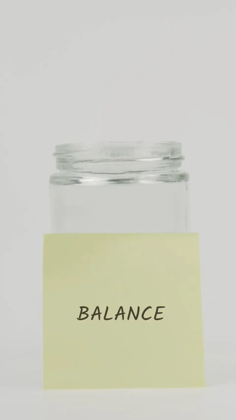 Balance text or word on yellow sticky note attached to glass jar with hand Stock Footage 311680423