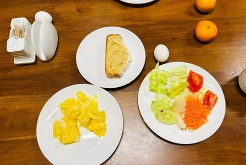 A balanced breakfast with scrambled eggs, toast, and fresh vegetables. Fotos de archivo
