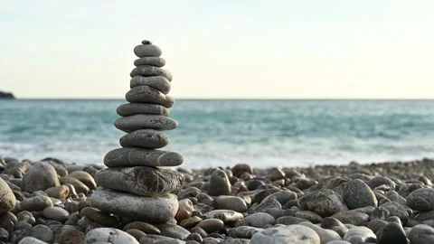 Balanced rock pyramid on pebbles beach against sea waves on background Vídeo Stock 238641524