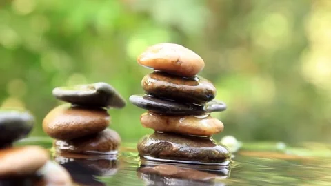 Balanced rocks pyramid with water drops surround it on water with Golden lig Stock-Footage 260200794