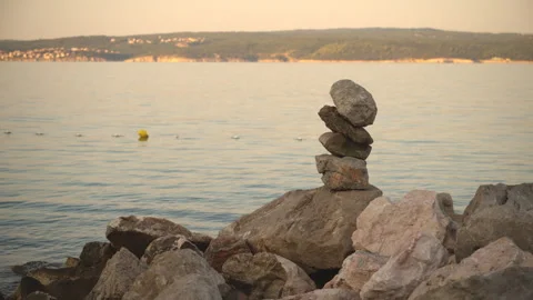 Balanced stack of stones on a rocky shore overlooking calm sea and a distan.. Stock Footage 342374602