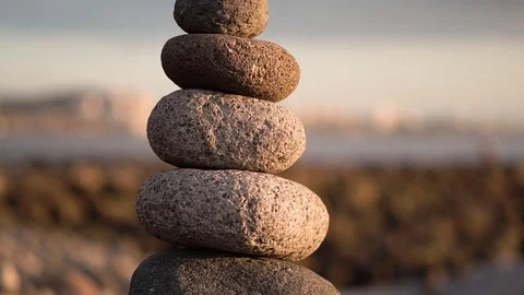 Balanced stone pyramide on shore of the ocean at dawn. Sea pebbles tower closeup Stock Footage 125769817