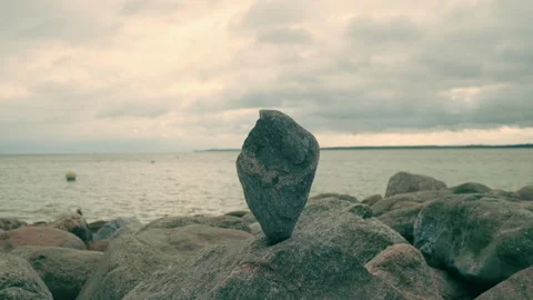 Balanced stone sculpture on a rocky beach by the sea at twilight Vídeos de archivo 346317308