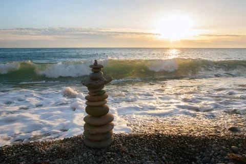 Balanced Stone Stack on a Pebble Beach at Sunset 库存照片