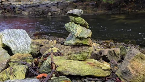 Balanced stone tower beside a flowing mountain stream Stock Footage 344058609