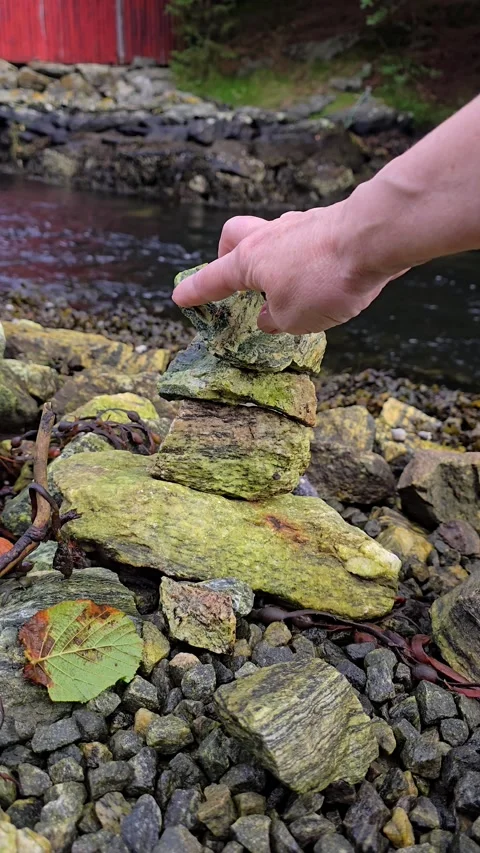 Balanced stone tower collapsing beside a flowing mountain stream Stock Footage 344058628