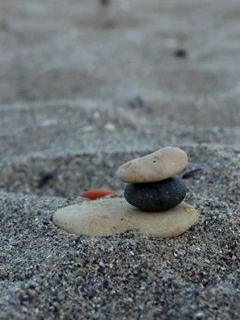 Balanced stones on sandy surface at the beach during late afternoon sunlight 스톡 사진