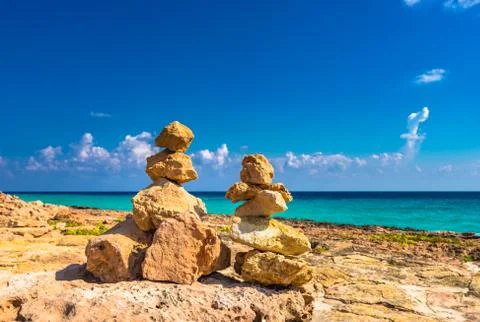 Balanced stones stack on beach with blue sunny sky Stock Photos
