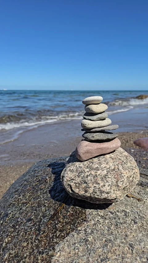 Balanced stones stack on beach with sea waves and blue sky Video stock 330109574