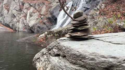 Balanced Tower of small tones assembled by a Waterfall in Autumn Stock Footage 317192153