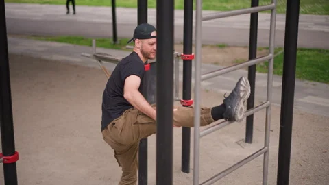 Balancing On Bars Outdoors, Man Performs Controlled Stretch In City Park Stock Footage 324756447