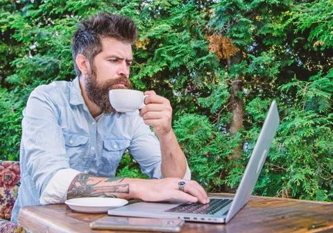 Balancing between work and pleasure. Hipster drinking tea and using computer Stock Photos