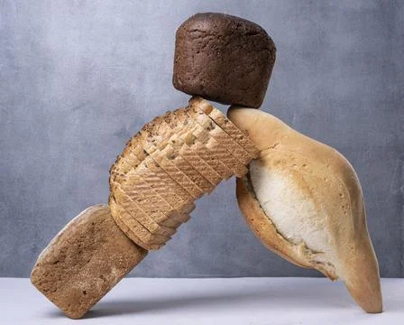 Balancing bread on a table on a gray background. Stock Photos