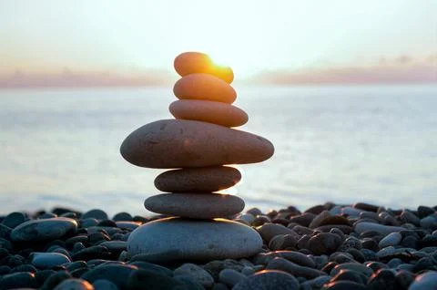 Balancing cairn of smooth stones on a seashore, illuminated by the soft ray.. Stock Photos