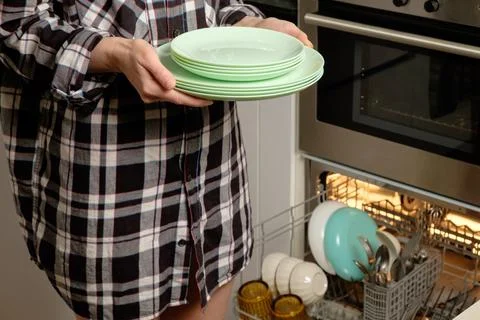 Balancing clean plates while managing the hustle of kitchen chores Stock Photos