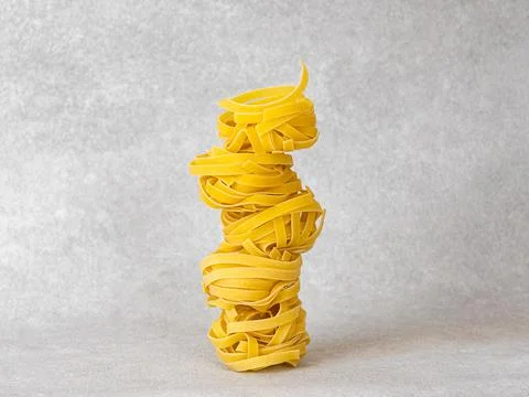 Balancing pasta nests in a stack on light grey background Stock Photos