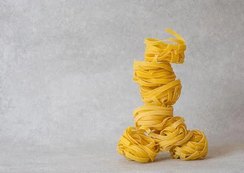 Balancing pasta nests in a stack on light grey background Stock Photos
