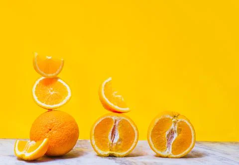 Balancing stack of fresh sliced oranges. Yellow background. Summer concept Stock Photos