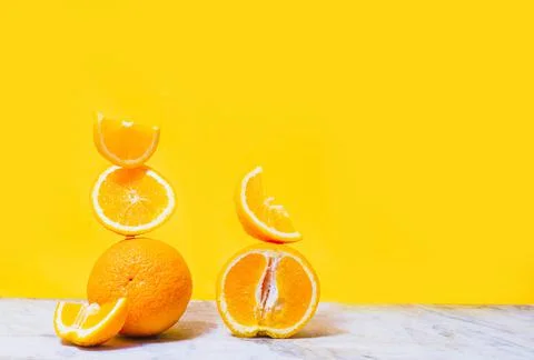 Balancing stack of fresh sliced oranges. Yellow background. Summer concept Stock Photos