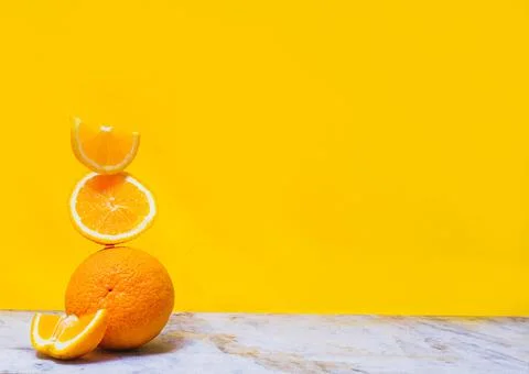 Balancing stack of fresh sliced oranges. Yellow background. Summer concept. C Stock Photos