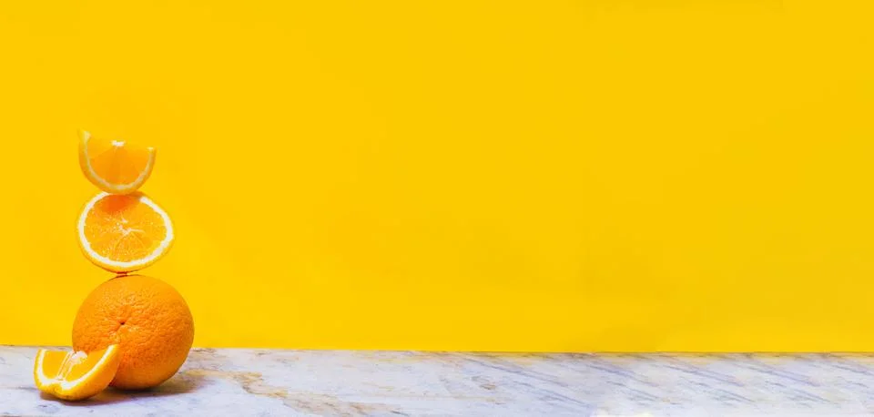 Balancing stack of fresh sliced oranges. Yellow background. Summer concept. C Stock Photos