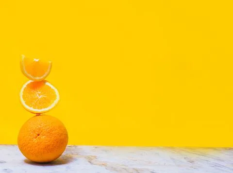 Balancing stack of fresh sliced oranges. Yellow background. Summer concept. C Stock Photos