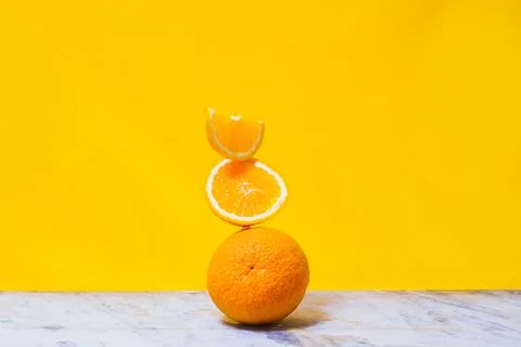 Balancing stack of fresh sliced oranges. Yellow background. Summer concept. N Stock Photos