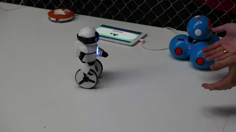 Balancing white robot on a table and female hands calling him Stock Footage 67250829