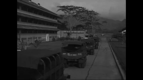 BALBOA, PANAMA - 1953: Vehicle column - Covered transports pass troop quarters Stock Footage 344500853