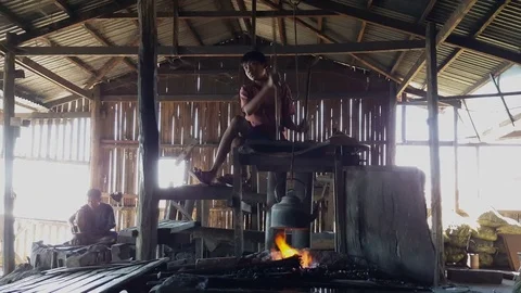 Balcksmith assistant uses traditional hand belows, fire under kettle, Inle lake Видео 79838534