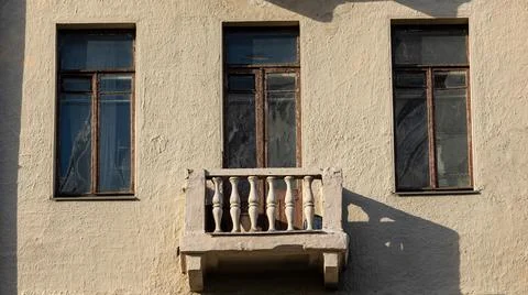 A balcony is located on the side of a building, featuring three windows Stock Photos