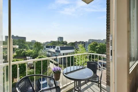 A balcony with a table and chairs overlooking a city Stock Photos