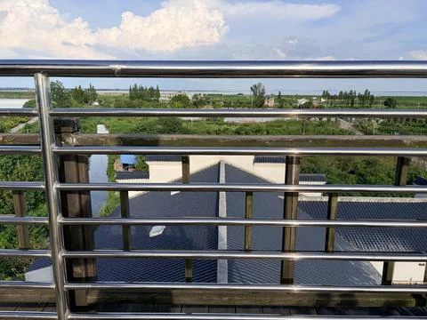 Balcony view of rooftops and greenery under a blue sky. Stock-Fotos