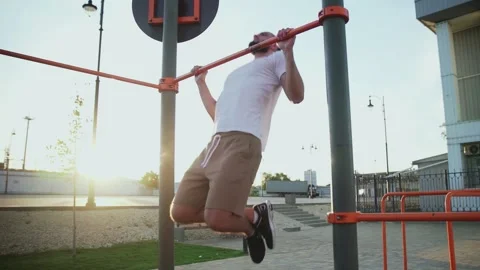 Bald and bearded man doing pull-ups on horizontal bar. On workout area near Stock Footage 143502437